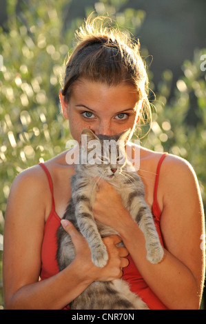 Giovane donna lookintg nella fotocamera, coccole con il suo gatto Foto Stock