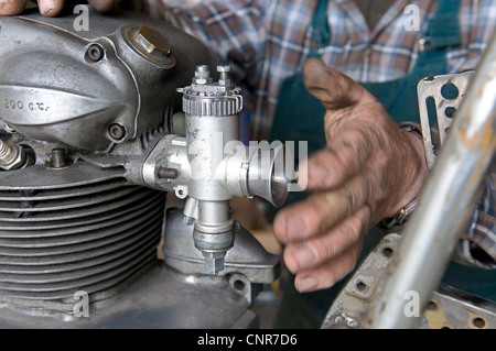 Uomo che ripara un moto d'epoca Foto Stock