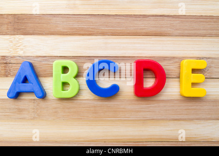 Lettera magneti "ABCDE" closeup su uno sfondo di legno Foto Stock