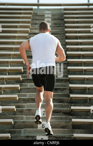 Uomo che corre su gradini in stadium, vista posteriore Foto Stock