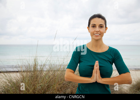 Donna matura la pratica dello yoga sulla spiaggia, ritratto Foto Stock