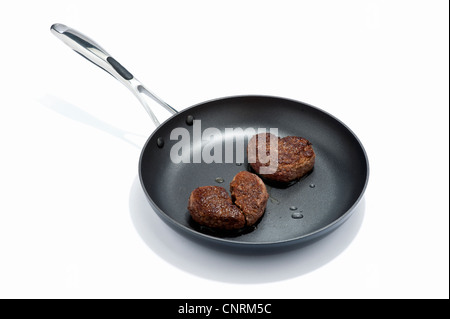 Due a forma di cuore hamburger di manzo in una padella, uno rotto Foto Stock