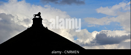 Lion Hill stagliano contro il cielo nuvoloso, monumento in memoria del 1815 Battaglia di Waterloo, Eigenbrakel vicino a Bruxelles, in Belgio Foto Stock