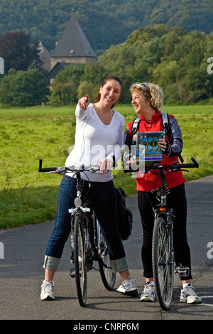 Due donne sulla Valle della Ruhr Cycleway cercando il modo giusto, Kemnade castle in background, in Germania, in Renania settentrionale-Vestfalia, la zona della Ruhr, Witten Foto Stock