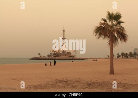 Una spiaggia in Kuwait City con la Marina edificio onde in background Foto Stock