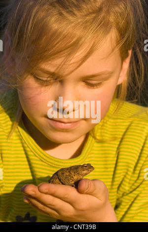 Europeo di rospo comune (Bufo bufo), la ragazza con un rospo comune sulla sua mano Foto Stock