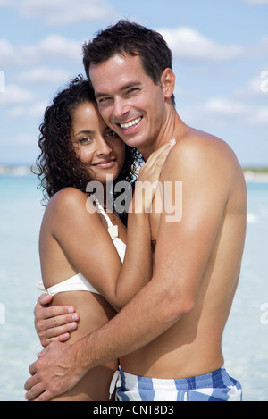 Giovane abbracciando in spiaggia, ritratto Foto Stock