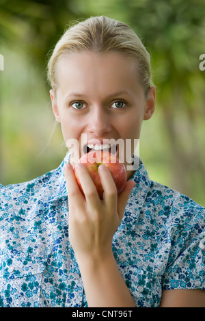 Giovane donna di mordere in apple, ritratto Foto Stock