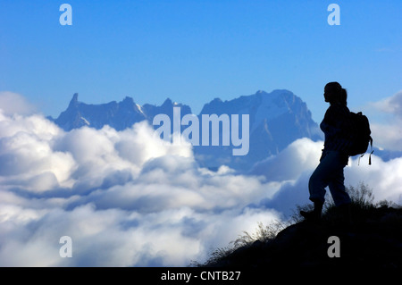 Silhouette di un escursionista di montagna di fronte al massiccio del Monte Bianco rottura attraverso una copertura nuvolosa, Francia, Alpi Foto Stock