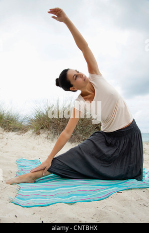 Donna matura fare yoga stretch sulla spiaggia, ritratto Foto Stock