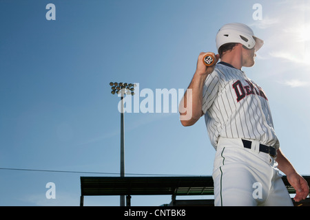 Giocatore di baseball azienda bat, guardando sopra la spalla Foto Stock