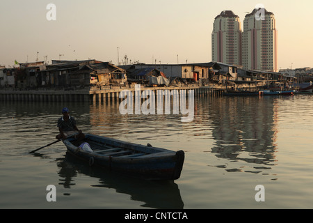 Baraccopoli zona con nuovi edifici dietro nello storico Porto di Sunda Kelapa a Jakarta, Indonesia. Foto Stock