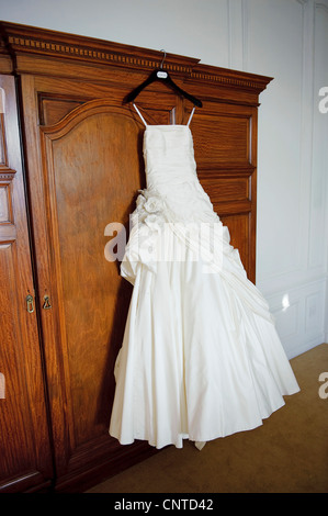 Avorio spose abito da sposa appeso dal guardaroba porta sulla mattina di nozze Foto Stock