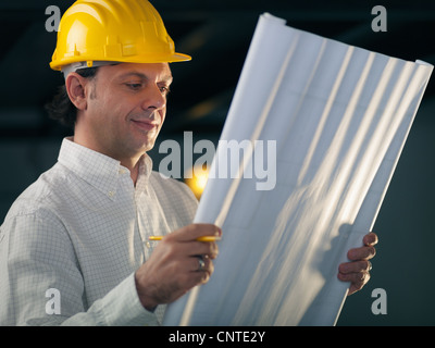 Uomo di mezza età lavorando come architetto e lettura del piano di costruzione in office Foto Stock