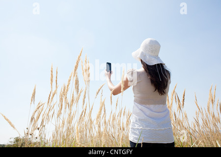 Donna di scattare le foto con il telefono cellulare Foto Stock