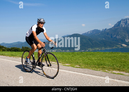 Uomo con una bici da corsa su un tour nelle montagne alpine, con il lago Traunsee dietro, Austria, Austria superiore, Gmunden Foto Stock