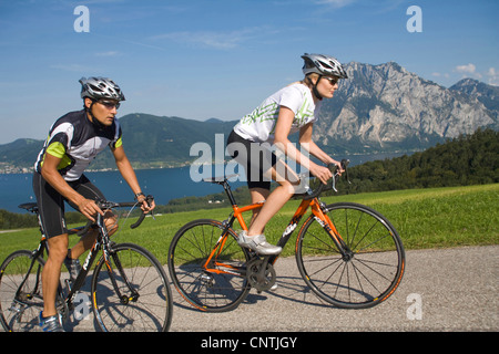 Uomo e donna con bici da corsa su un tour nelle montagne alpine, con il lago Traunsee dietro, Austria, Austria superiore, Gmunden Foto Stock