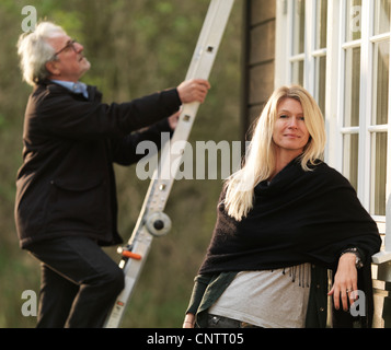 Donna sorridente come marito si arrampica scaletta Foto Stock