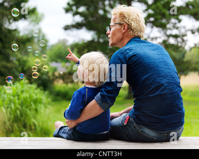 Padre e figlio ammirando le bolle all'aperto Foto Stock