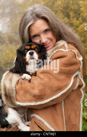 Donna anziana abbracciando il cane all'aperto Foto Stock