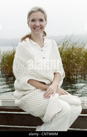 Donna anziana seduta sul dock in legno Foto Stock