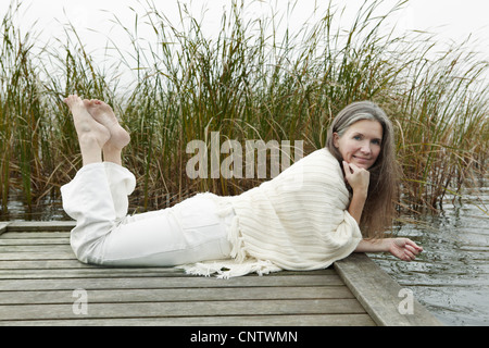 Donna anziana rilassante sul dock in legno Foto Stock