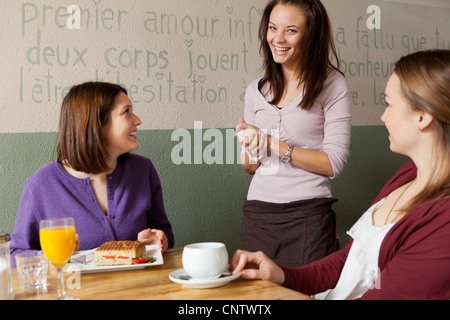 Le donne parlano di cameriera in cafe Foto Stock