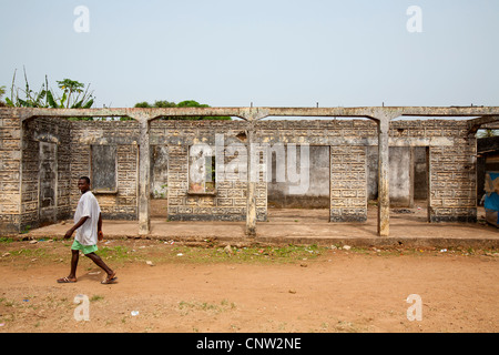 L'uomo africano camminare vicino a casa distrutta, vicino a Kenema, in Sierra Leone Foto Stock