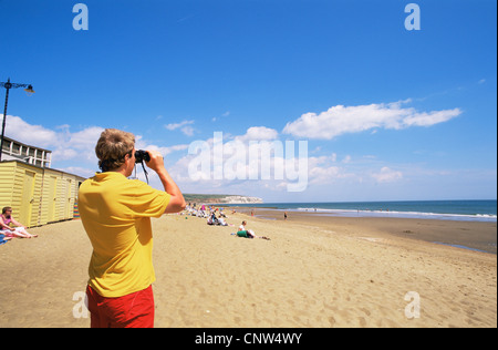 Regno Unito, Gran Bretagna, Inghilterra, Hampshire, Isle of Wight, Sandown, bagnino guardando attraverso il binocolo sulla spiaggia di Sandown Foto Stock