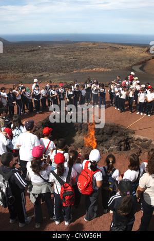 Emblazing una balla di fieno da gallerie sotterranee di calore nella parte anteriore di un sacco di visitatori delle montagne vulcaniche, Isole Canarie Lanzarote, Parco Nazionale di Timanfaya Foto Stock