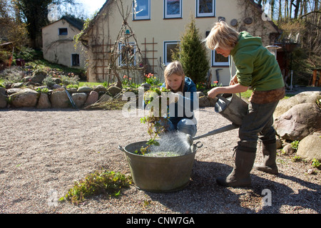 Ortica (Urtica dioica), donna con sua figlia la produzione di ortica slurry da ortiche fresche ecologico per il controllo di parassiti e fertilizzante, Germania Foto Stock