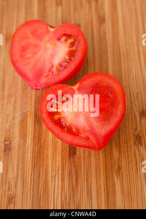 Dire che con i pomodori - a forma di cuore il pomodoro tagliato a metà su un tagliere di legno Foto Stock