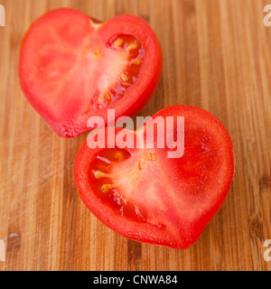 Dire che con i pomodori - a forma di cuore il pomodoro tagliato a metà su un tagliere di legno Foto Stock