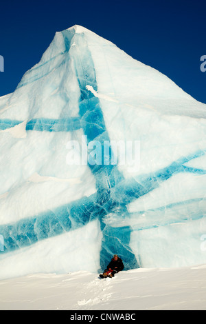 Uomo seduto nella neve davanti di iceberg con venature blu, Groenlandia, Ostgroenland, Tunu, Kalaallit Nunaat, Liverpool Land, Lillefjord Foto Stock