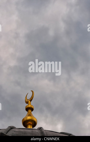 Un islamico mezzaluna simbolo sulla sommità di una cupola della moschea sullo sfondo di un cielo moody. Foto Stock