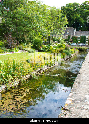 Vista di Bibury allevamento di trote nel grazioso English Cotswold village di Bibury in Gloucestershire England Regno Unito.Swan Hotel in distanza. Foto Stock