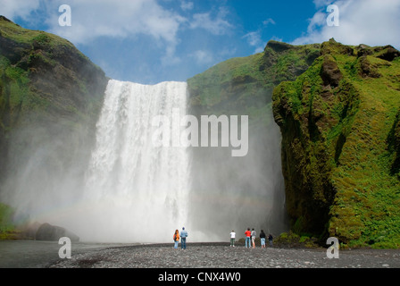 I visitatori al Riverside di Skoga di fronte all'impressionante cascata Skogafoss, Islanda, Skogar Foto Stock