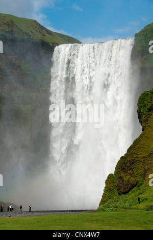 I visitatori al Riverside di Skoga di fronte all'impressionante cascata Skogafoss, Islanda, Skogar Foto Stock