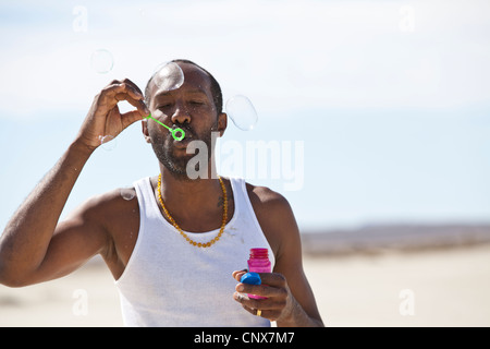 Uomo a soffiare bolle nel deserto. Foto Stock