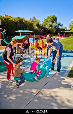 Giovani e vecchi membri dello staff aiutare i ciechi e storpi i bambini utilizzano il parco giochi presso la Tenda per bambini Centro di apprendimento. Foto Stock