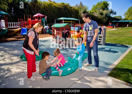 Giovani e vecchi membri dello staff aiutare i ciechi e storpi i bambini utilizzano il parco giochi presso la Tenda per bambini Centro di apprendimento. Foto Stock