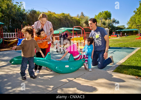 Giovani e vecchi membri dello staff aiutare i ciechi e storpi i bambini utilizzano il parco giochi presso la Tenda per bambini Centro di apprendimento. Foto Stock