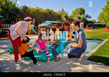 Giovani e vecchi membri dello staff aiutare i ciechi e storpi i bambini utilizzano il parco giochi presso la Tenda per bambini Centro di apprendimento. Foto Stock