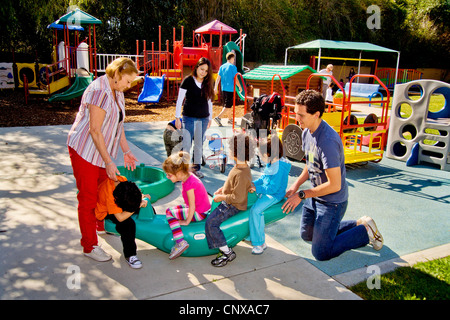 Giovani e vecchi membri dello staff aiutare i ciechi e storpi i bambini utilizzano il parco giochi presso la Tenda per bambini Centro di apprendimento. Foto Stock