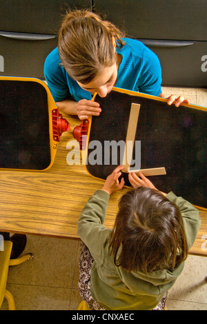 L insegnante di una necessità speciale di pre-scrittura Braille classe i bambini ciechi del Centro di apprendimento inizia con "L". Foto Stock