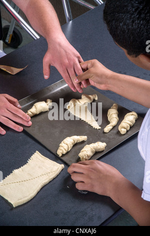 Un insegnante aiuta un handicap ipovedenti teenager fare rotoli da toccare dalla pasta preparata in una classe di cucina. Foto Stock