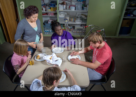 Un insegnante si unisce a lei cieca e studenti handicappati cibo di campionamento sono realizzati in una lezione di cucina presso la Tenda Centro per l'infanzia. Foto Stock