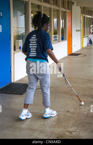 Usando un bastone bianco, un afro-americano di preteen girl trova il suo modo a bambini ciechi il Learning Center di Santa Ana CA. Foto Stock