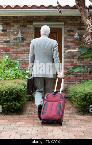 Un imprenditore che arrivano a casa da un viaggio Foto Stock