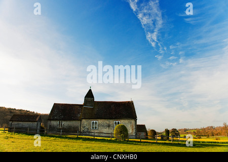 St Hubert della cappella di Hampshire Idsworth mattina presto con campo di colza in background e cielo blu con nuvole Foto Stock